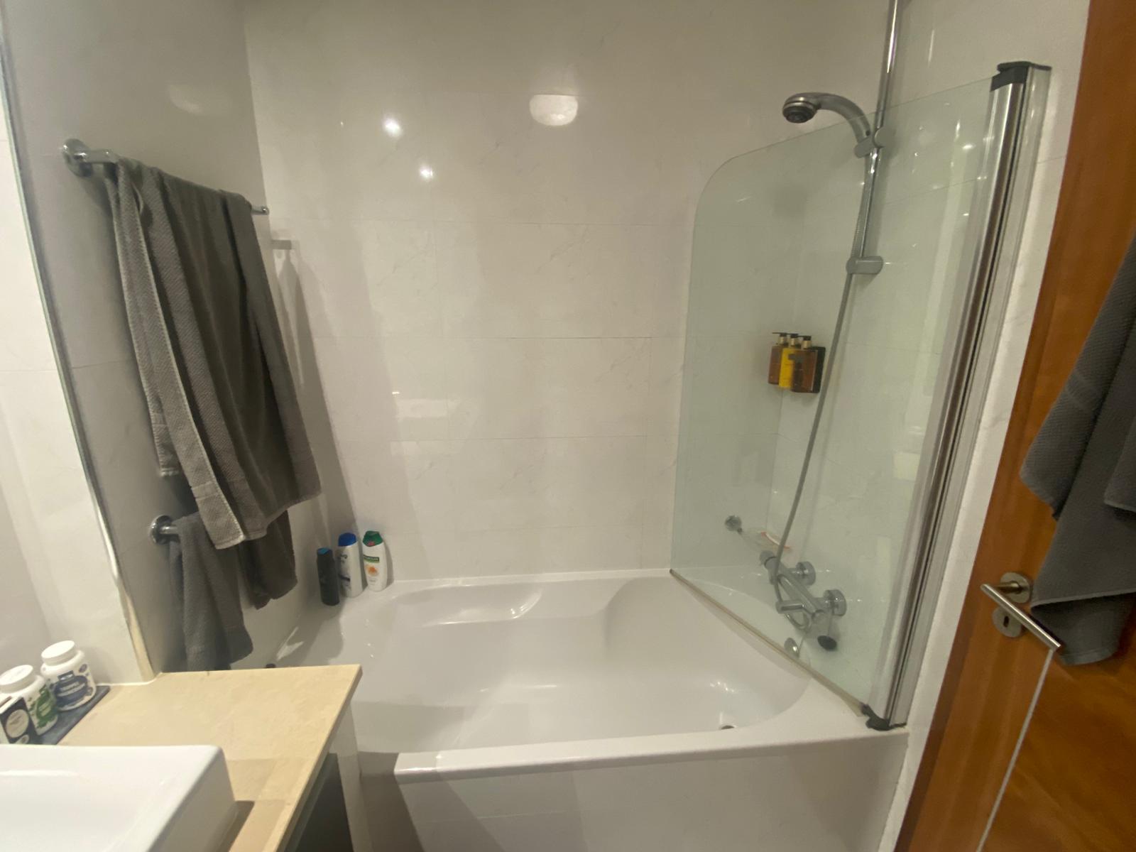 Bathroom before conversion with bath and shower screen